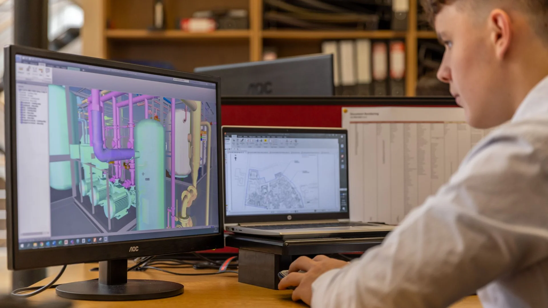 Fotografia referencyjna: Inżynier pracujący z oprogramowaniem CAD na dwóch monitorach w biurze projektowym – jak przygotować model CAD do wizualizacji 3D produktu
